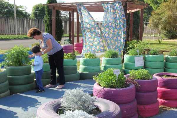 Adulto e criança explorando jardim sensorial com plantas não tóxicas e seguras