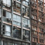 Fachada de predio urbano com varios ar-condicionados nas janelas representando ambientes fechados com ma ventilacao e Sindrome do Edificio Doente
