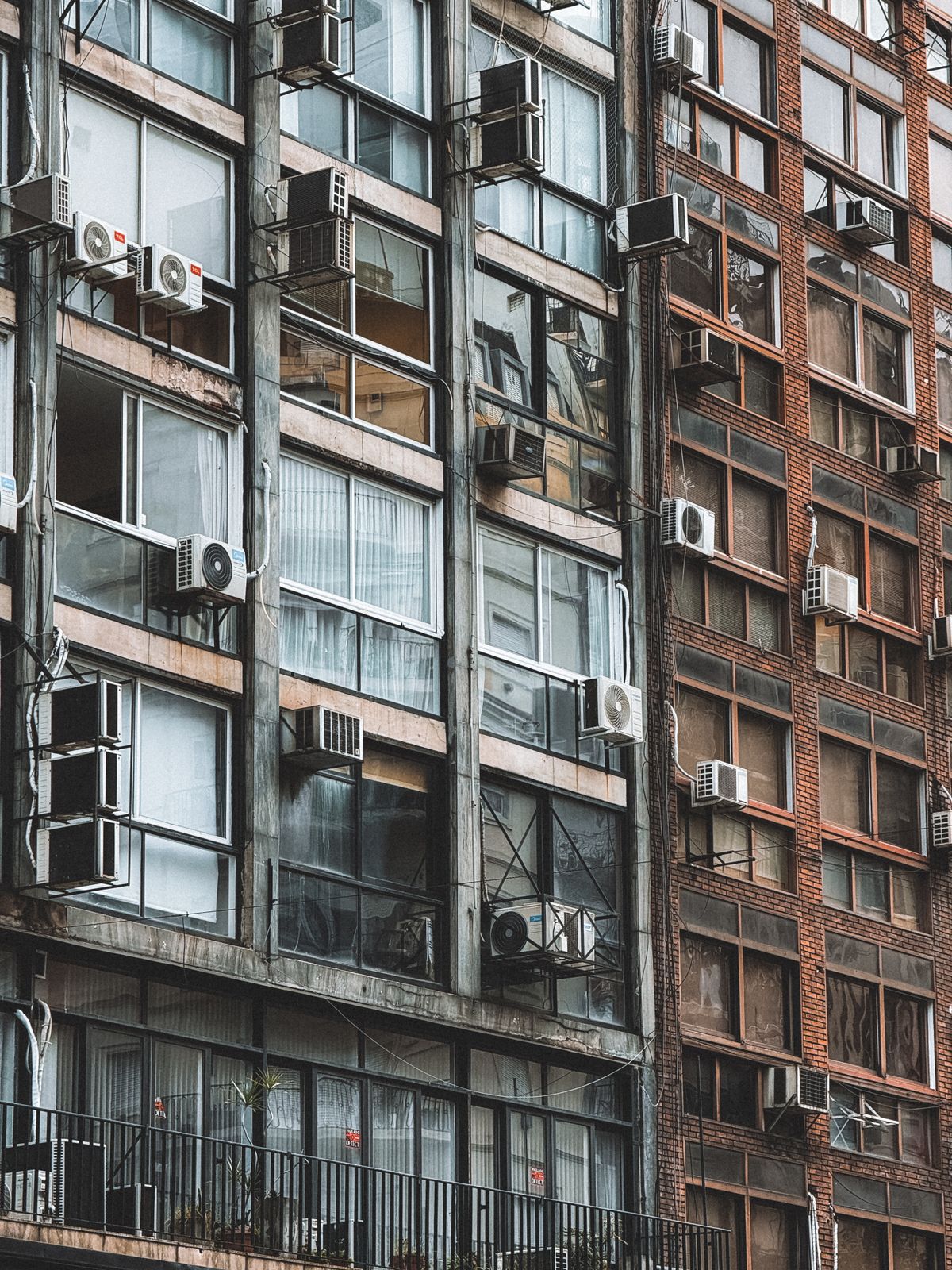 Fachada de predio urbano com varios ar-condicionados nas janelas representando ambientes fechados com ma ventilacao e Sindrome do Edificio Doente