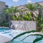 Piscina com cascata de pedra e jardim tropical, resultado de projeto de paisagismo bem planejado