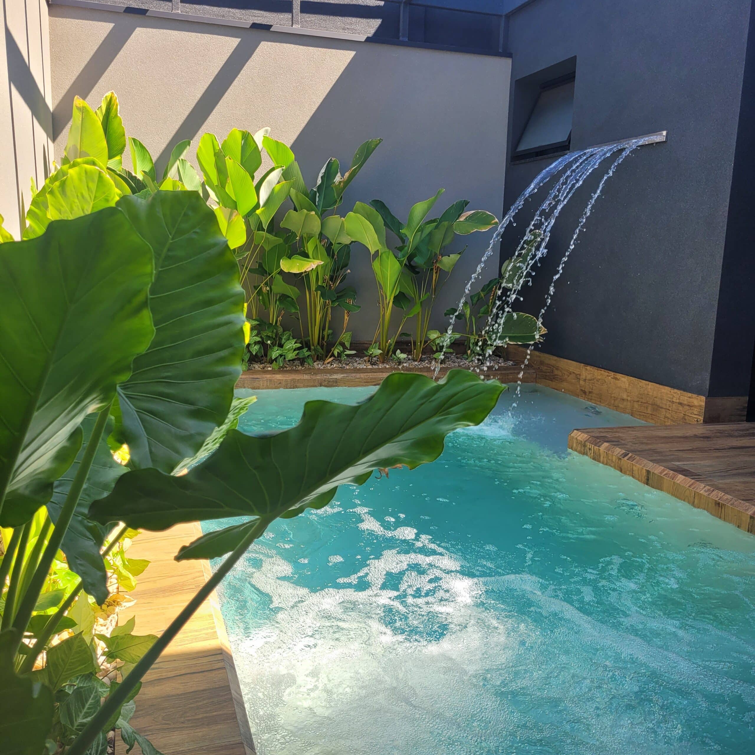 Piscina pequena com cascata, exemplo de espaço compacto que entra no escopo da consultoria de paisagismo online