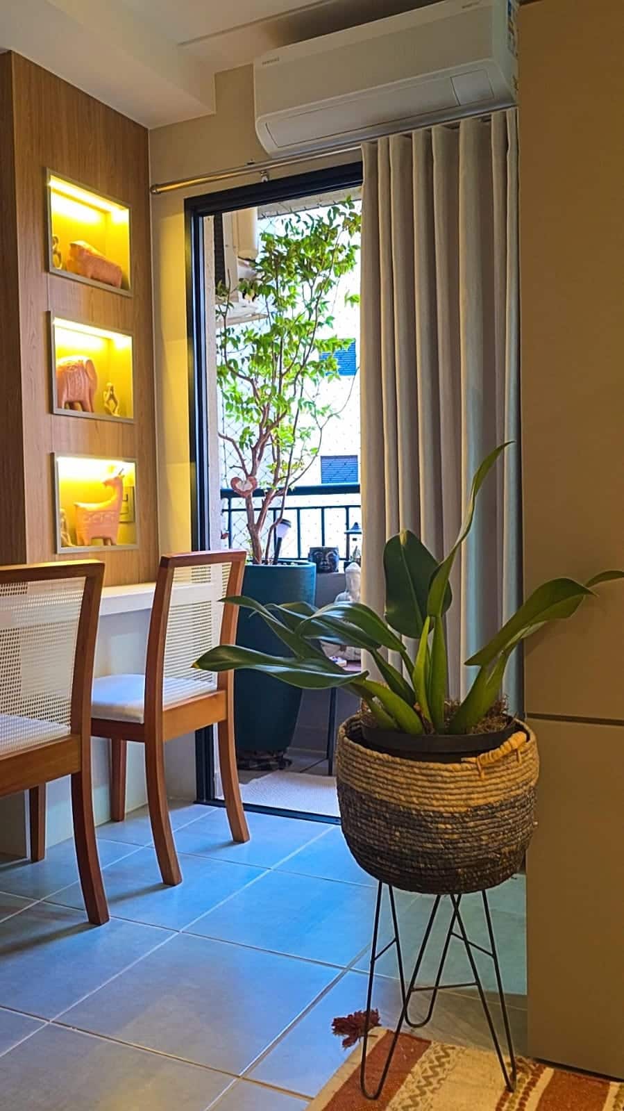 Mesma sacada de apartamento depois da consultoria de paisagismo online, com arvore em vaso, planta em cesto e nichos iluminados