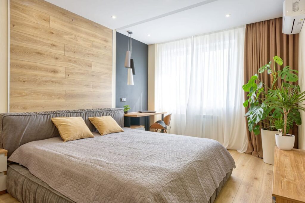Quarto biofílico em tons neutros e madeira com plantas junto à janela