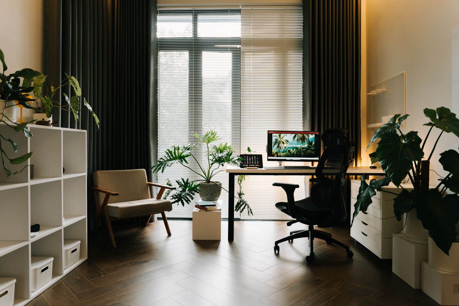 Home office com Guaimbê em vaso e luz natural filtrada pela persiana