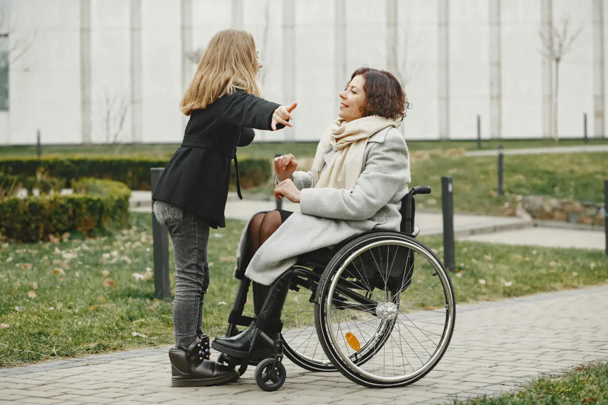 Paciente em cadeira de rodas conversando em jardim com caminho acessível, biofilia em hospitais