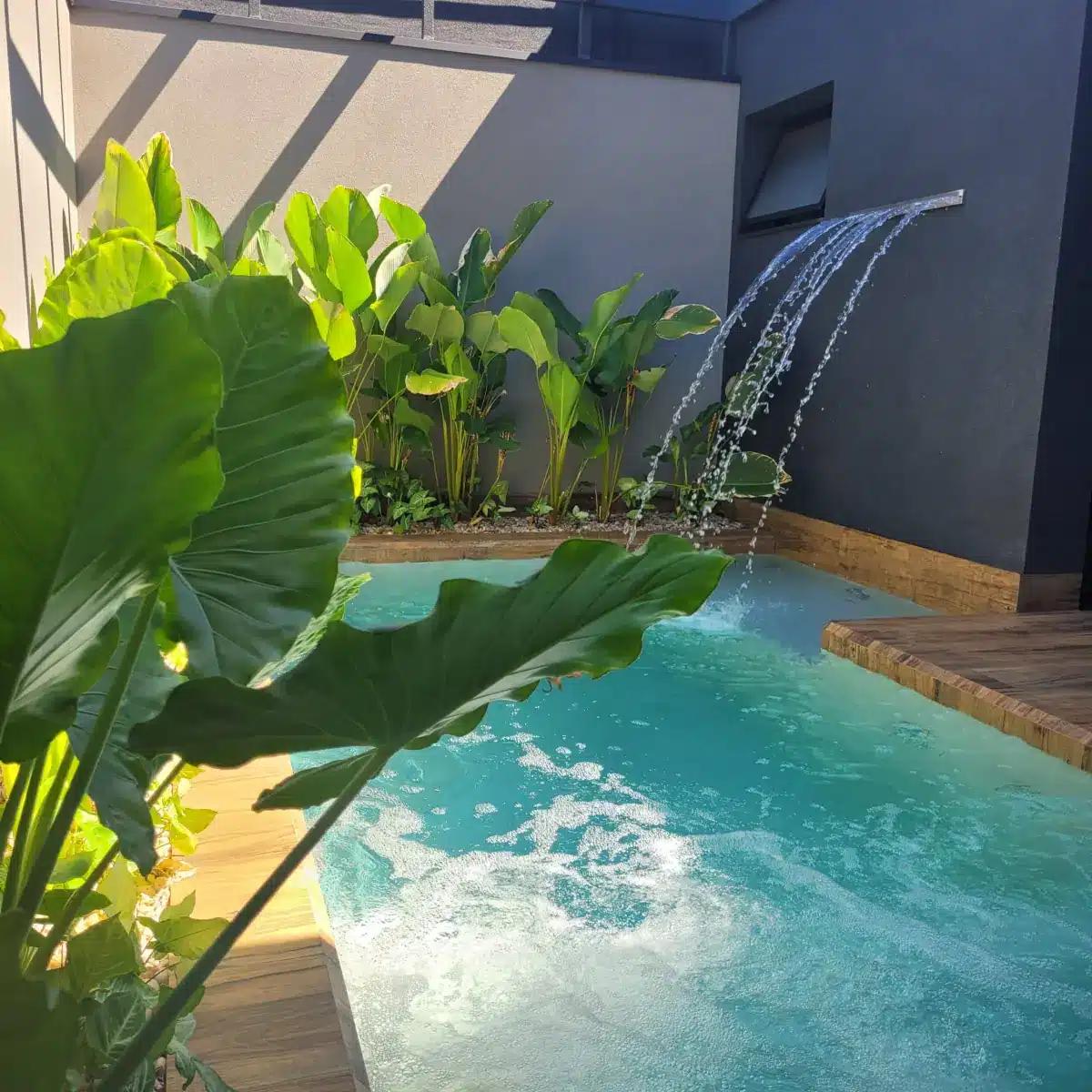 Piscina pequena com cascata, exemplo de espaço compacto que entra no escopo da consultoria de paisagismo online
