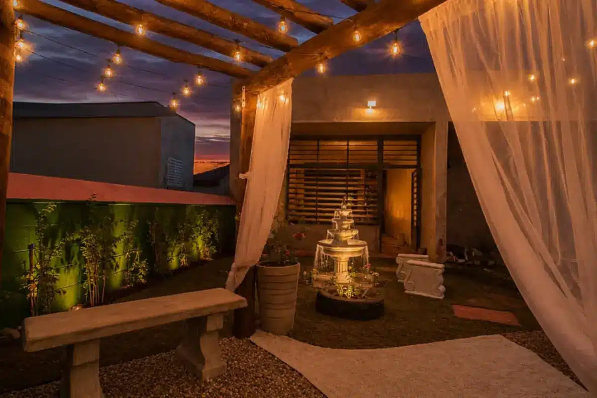 Jardim sensorial da escola à noite, com varal de luzes, cortinas e fonte iluminada